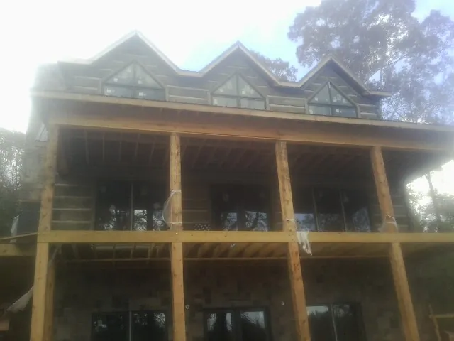 Dormers and porch framing on a large log home under construction — Roof Coating work by our crew in Wakefield