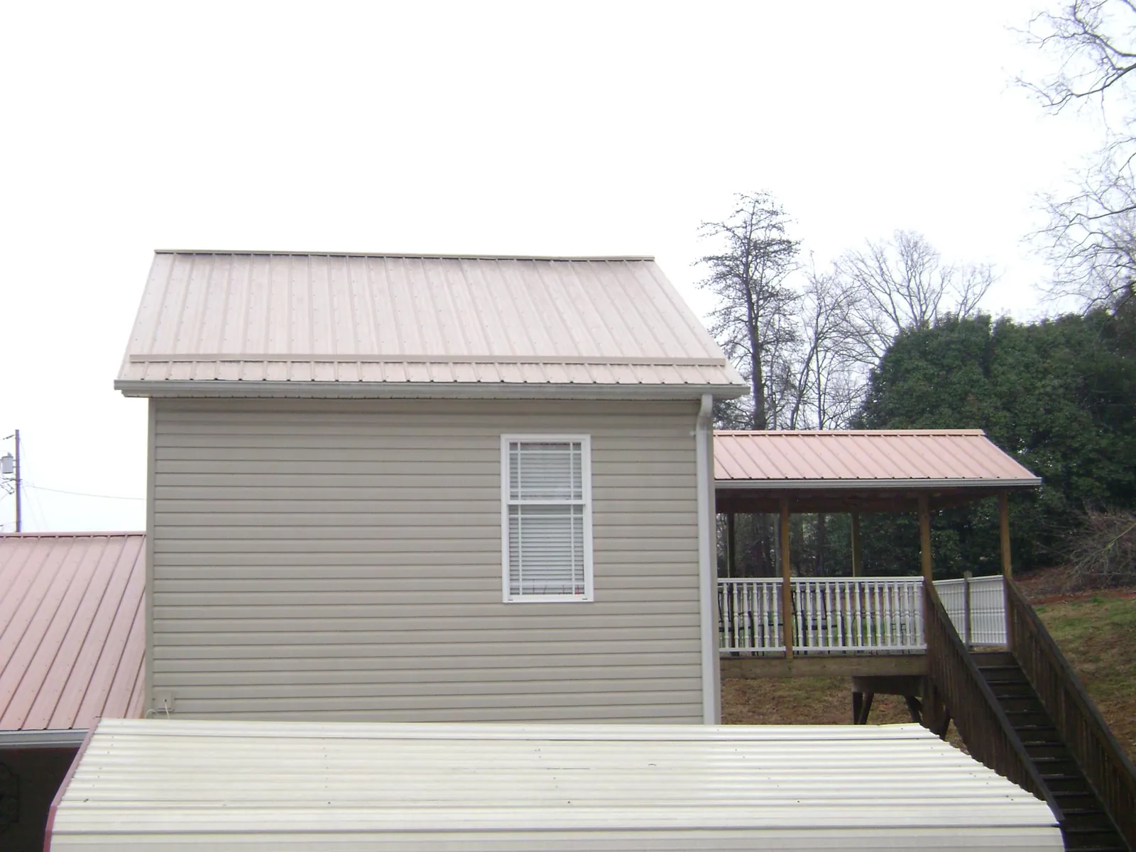 Tan metal roofs on a two story addition and attached porch, from a Roof Replacement job in Wakefield