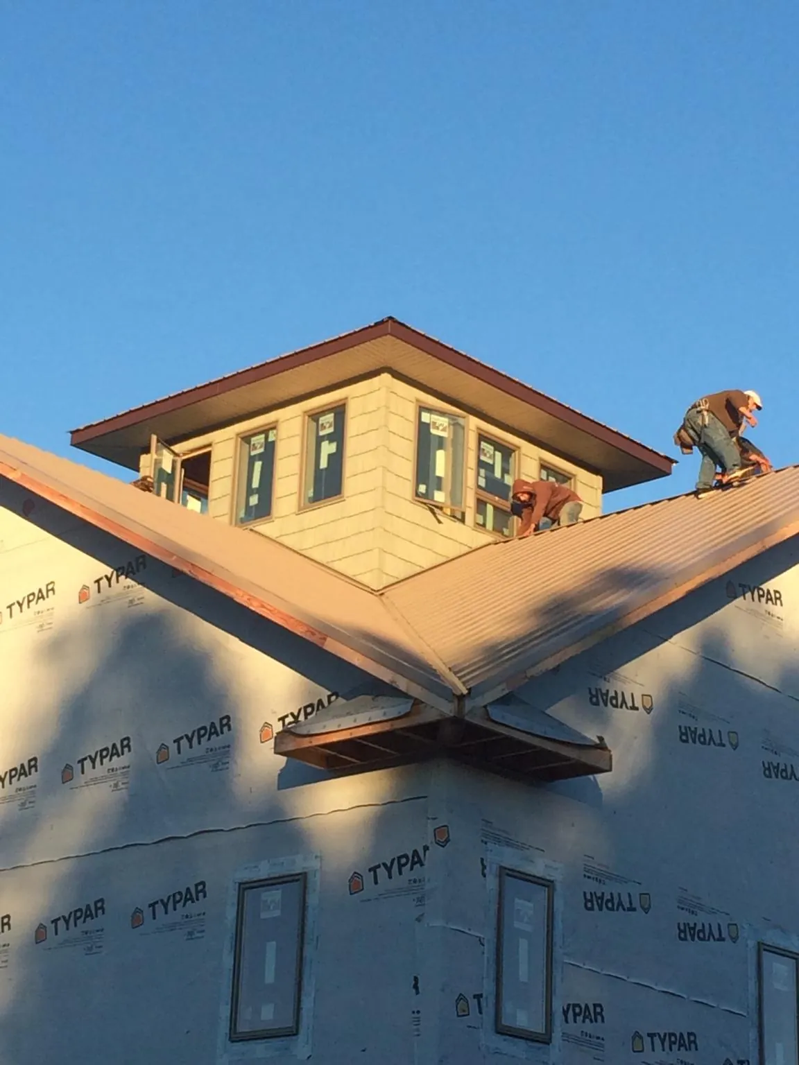 Roofers working around a rooftop cupola on a new metal roof at sunset — Roof Waterproofing in Wakefield by Roofing Brothers